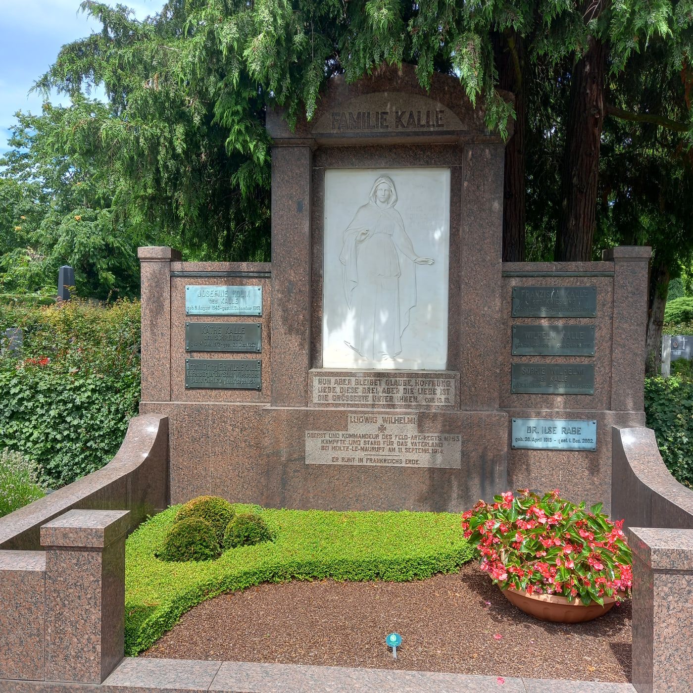 Monumentales rötliches Familiengrab Kalle mit hellem Figurenrelief und seitlichen Namenstafeln auf Friedhof Biebrich