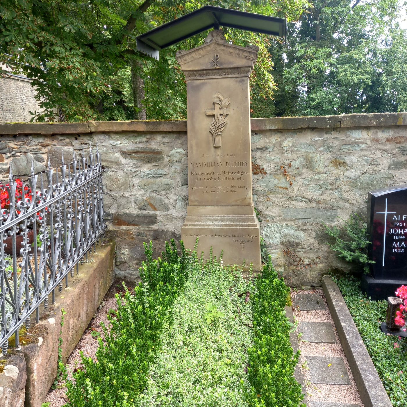 Hohe Grabstele Maximilian Diltheys mit Giebel, Kreuz- und Pflanzenrelief und flachem Schutzdach auf Friedhof Biebrich
